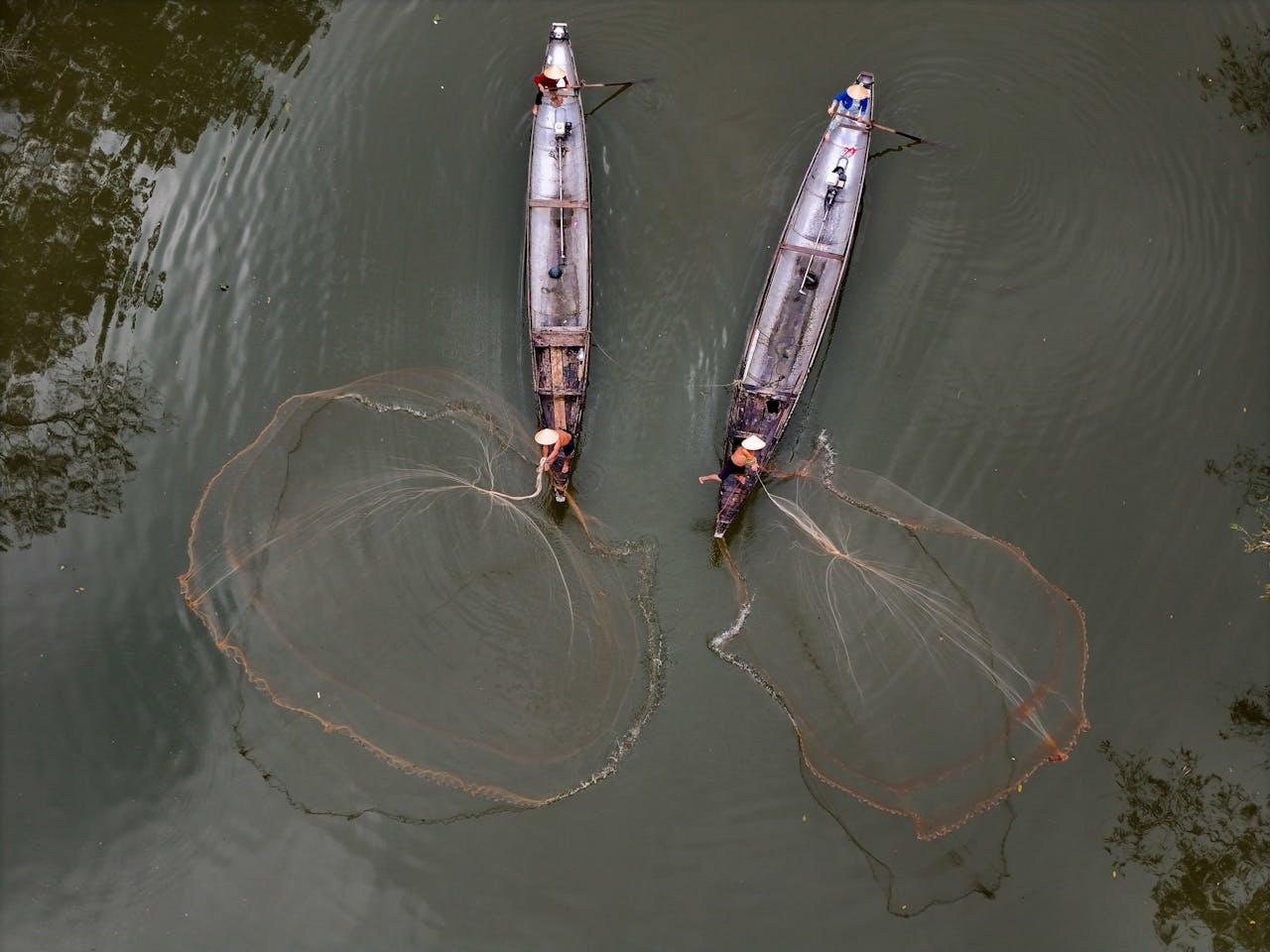 Aerial shot of fishermen casting nets from boats in Hue, Vietnam.